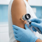 Un dermatologue examine le grain de beauté d'un patient avec un dermatoscope dans un cabinet médical.