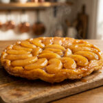 Une tarte Tatin chaude et fumante posée sur une planche en bois dans une cuisine rustique.