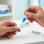 Une personne utilise un kit d'autotest d'allergie Aller-Check en déposant une goutte de réactif sur la cassette.