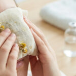 Une personne applique une compresse de camomille sur ses yeux pour soulager une irritation.