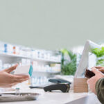 Un pharmacien remet une boîte de vaccin à un client au comptoir d'une officine.