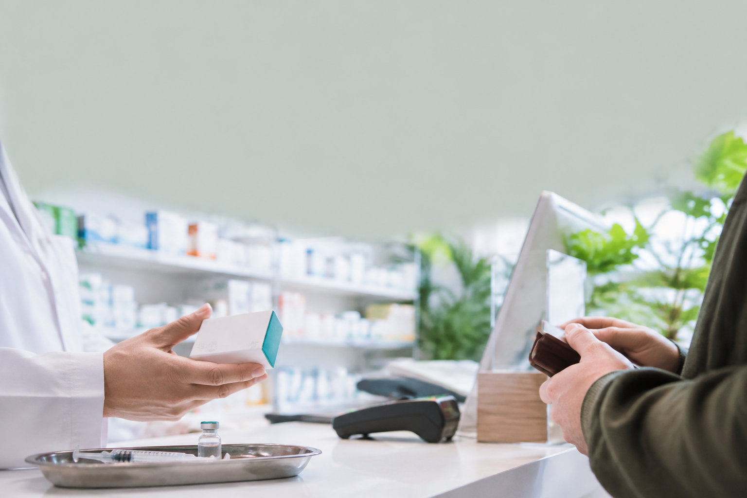 Un pharmacien remet une boîte de vaccin à un client au comptoir d'une officine.